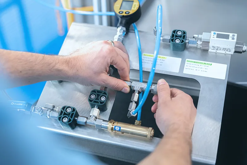Un technicien effectue l'installation et la maintenance d'un système pneumatique industriel, ajustant des composants comme les vannes et les tuyaux pour assurer le bon fonctionnement du système.