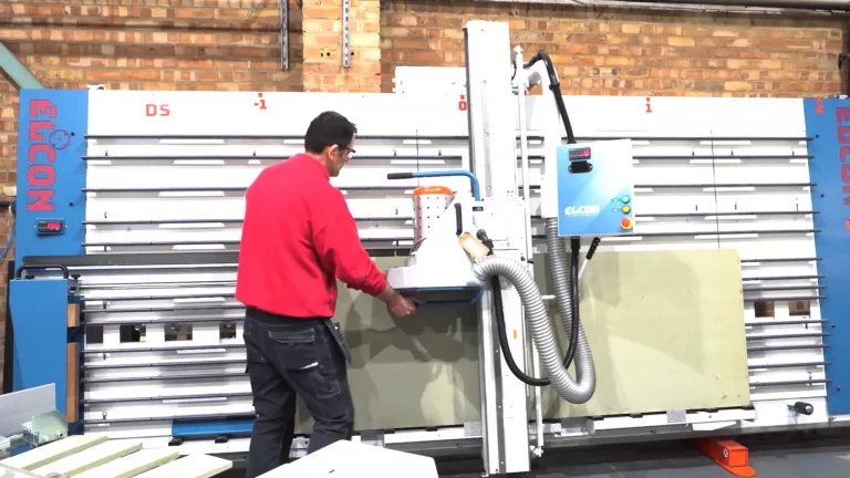 Technicien utilisant une scie à panneau verticale Elcon pour la découpe de panneaux en menuiserie ou industrie du bois.