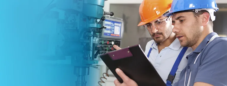 Deux techniciens en maintenance industrielle analysant des données sur une machine-outil en atelier.