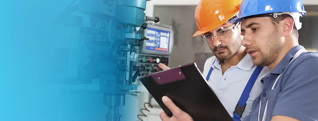 Deux techniciens en maintenance industrielle analysant des données sur une machine-outil en atelier.